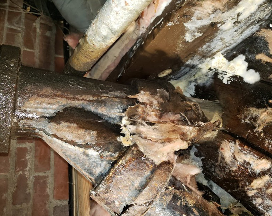 Broken cast iron drain pipe with severe corrosion and structural failure