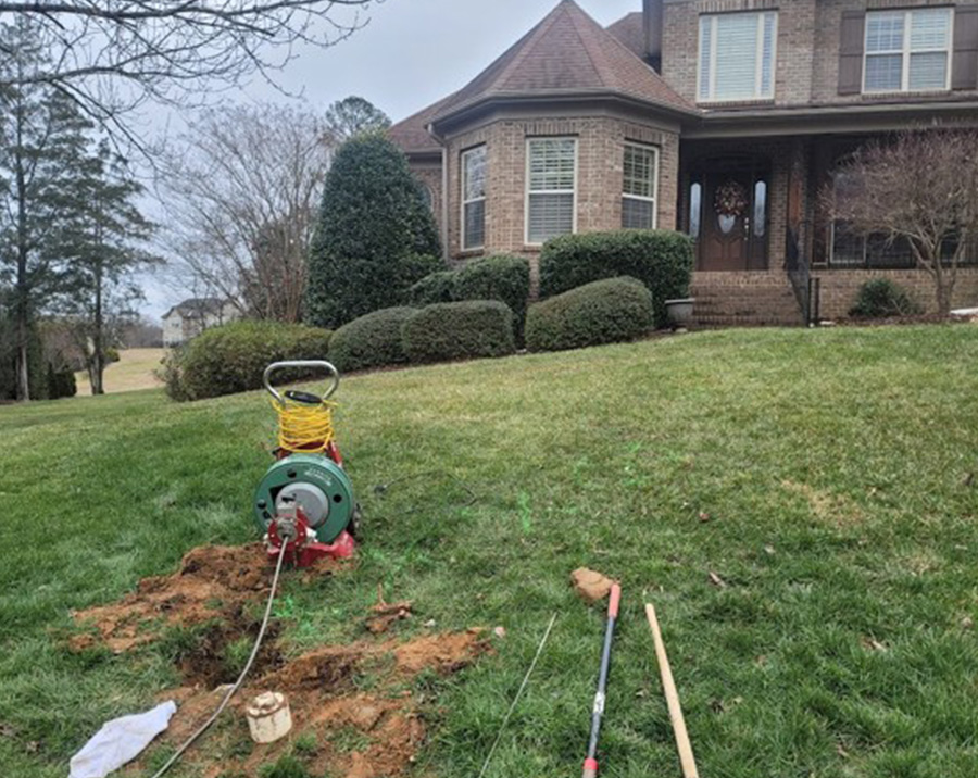 Drain cleaning machine clearing underground residential drain line from yard cleanout