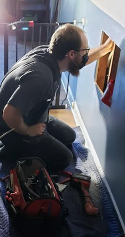Plumbing technician inspecting a leak inside a wall in a Matthews, NC home